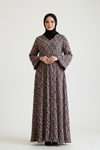 Woman wearing a patterned dress and black hijab on a white background