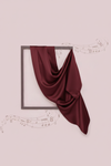 Maroon fabric draped over a square frame on a light pink background