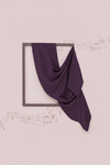Purple fabric draped over a black frame on a light pink background