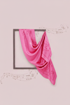 Pink scarf draped over a framed picture on a light pink background