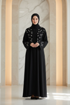 Woman wearing a black abaya with floral patterns in a marble hallway