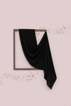 Black scarf draped over a framed picture on a light pink background