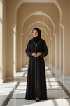 Woman in a black abaya standing in a sunlit hallway with arches