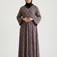 Woman wearing a patterned dress and black hijab on a white background