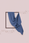 Blue fabric draped over a framed picture on a light pink background