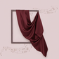 Maroon fabric draped over a square frame on a light pink background