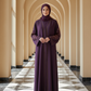 Woman in a long, dark purple dress standing in a hallway with arches.