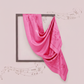 Pink scarf draped over a framed picture on a light pink background