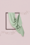 Green fabric draped over a framed picture on a pink background with musical notes.