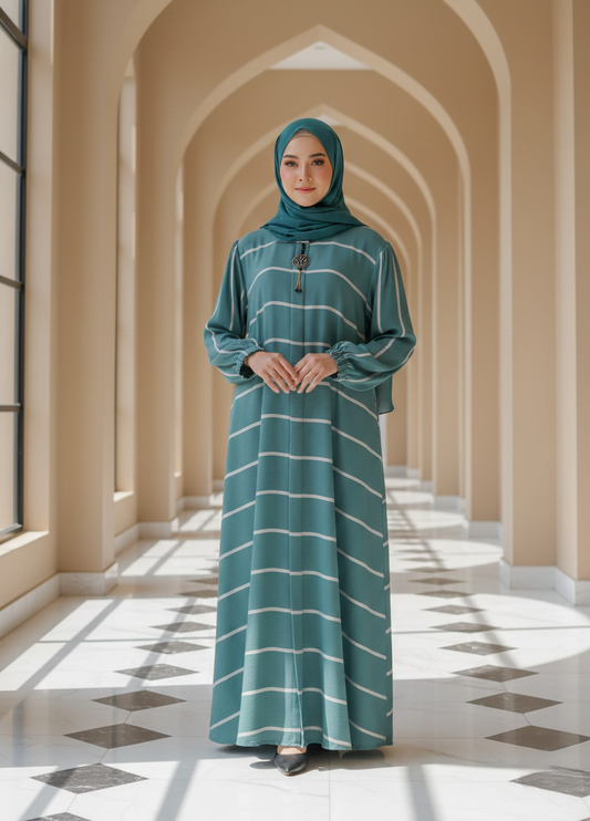 Woman in a teal dress with white stripes standing in a sunlit hallway with arches.