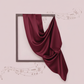Maroon fabric draped over a rectangular frame on a light pink background with decorative elements.