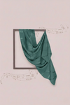 Green fabric draped over a square frame on a light pink background